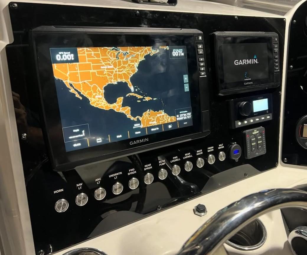 Twin Garmin displays set into a custom-cut acrylic helm panel with engraved switch legends