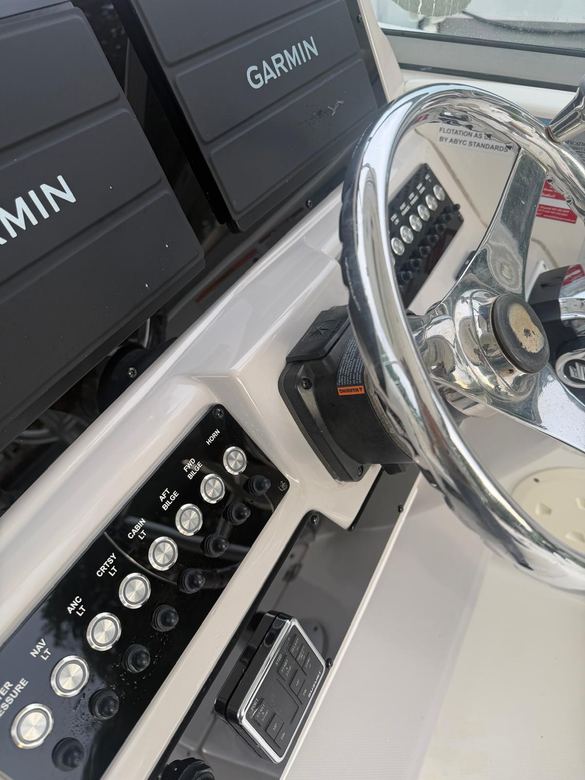 Twin Garmin displays beside a labeled stainless switch panel and Suzuki trim controls