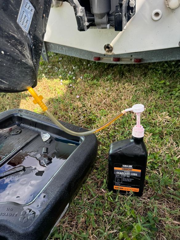 Lower unit gearcase lube drained into a pan and refilled during routine outboard maintenance