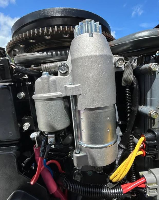 New starter motor and flywheel exposed during an outboard starting-system repair